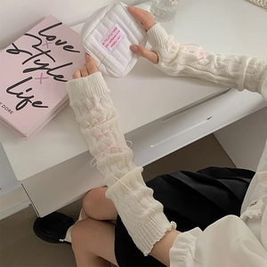 Close-up of cable knit white arm warmer with pink satin ribbon bow and sweet Lolita style