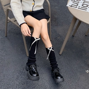 Black knit leg warmers with white ribbons paired with glossy platform loafers
