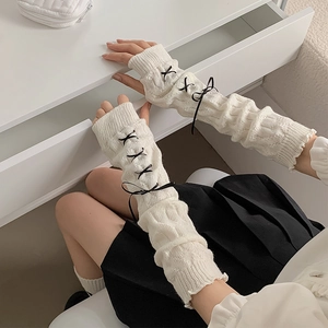 Detail of white chunky knit arm warmers with black bow ribbons in Lolita style