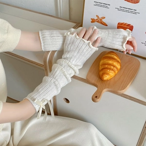 Knitted cream white leg warmers with bows and ruffled edges in a cozy aesthetic setting