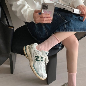 Vue détaillée de chaussettes montantes roses avec des baskets rétro crème et vert