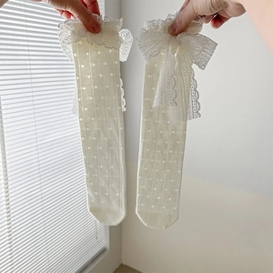 Détail de chaussettes blanc crème avec nœud en dentelle et texture en maille à pois fins