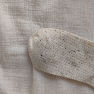 Close-up of ribbed knit texture on colorful speckled beige cotton college style socks