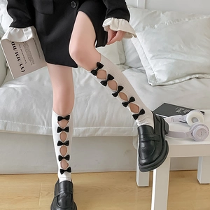 Detail of white knee-high socks with black bows and lace hollow design in JK style