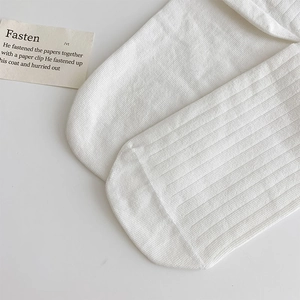 Macro shot of white ribbed cotton socks showing seamless toe stitching and soft texture