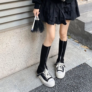 Detail of black ribbed knit leg warmers with side silver zipper and streetwear style