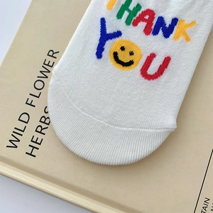 Detail of white cotton low cut socks featuring colorful THANK YOU text and yellow smiley face