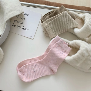 Close-up of pastel nep yarn knit socks with colorful flecks and ribbed cuff details