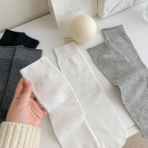 Close-up of ribbed cotton socks in white, black, and grey with breathable knit texture