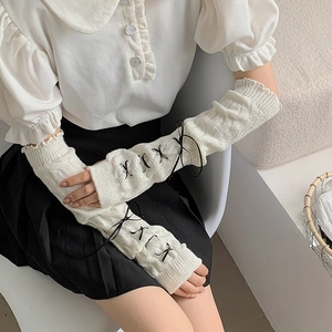 Macro detail of white cable knit arm warmers with black ribbons in Lolita style