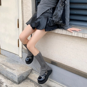 Detail of gray knitted leg warmers with zipper design paired with black platform shoes