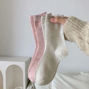 Detail of pink and beige cotton knit socks with colorful speckled dot patterns and ribbed cuffs