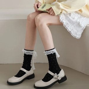 Détail de chaussettes noires à pois avec dentelle blanche et nœuds en ruban élégants