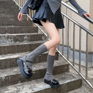 Detail of grey knitted leg warmers with side zipper paired with black platform shoes