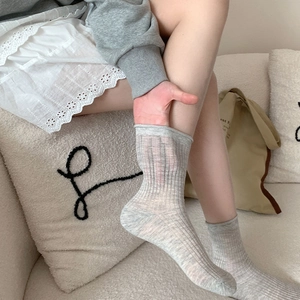 Détail de chaussettes en coton gris clair avec maille côtelée et bordure roulée