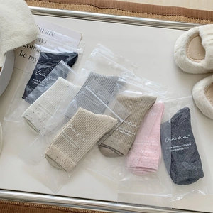 Set of seven colorful speckled cotton crew socks with minimalist branded zipper packaging