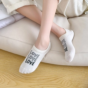 Close-up of white low-cut invisible socks with black LOVE lettering on breathable cotton