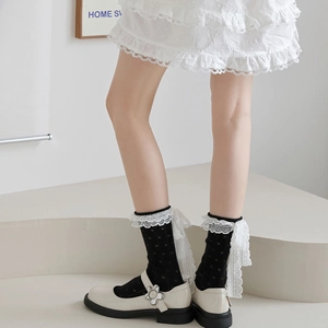 Détail de chaussettes noires à pois avec dentelle blanche et nœud en chaussures Mary Jane