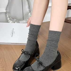 Dark gray knitted crew socks with ribbed texture paired with black Mary Jane shoes