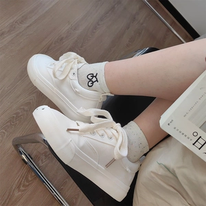 Detail of white canvas sneakers and beige cotton socks with mini embroidered patterns