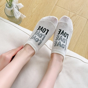 Close-up of white breathable low-cut socks with black LOVE print and heart-pattern details