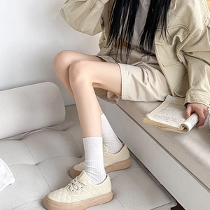 Close-up of beige vertical striped mid-calf socks paired with quilted canvas sneakers