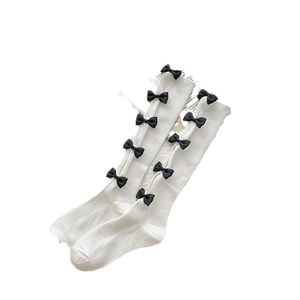 White Lolita knee-high socks featuring black satin bows and ribbed knit texture