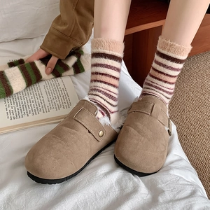 Mules en daim marron avec doublure en fourrure et chaussettes thermiques rayées au lit