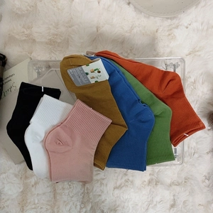 Colorful mid-calf cotton socks in seven candy colors on a cozy white plush carpet