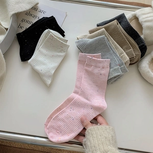 Close-up of knit cotton mid-calf socks with colorful speckles in multiple soft pastel colors