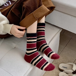 Détail de chaussettes en peluche à rayures rouges, noires et beiges pour l'hiver