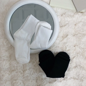 Thickened black and white crew socks with ribbed cuffs on a soft faux fur rug background