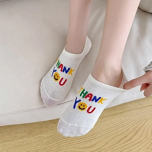 Close-up of white cotton low-cut socks featuring a yellow smiley face and Thank You text