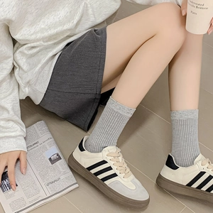 Women's beige suede casual sneakers with black stripes and brown gum sole on floor