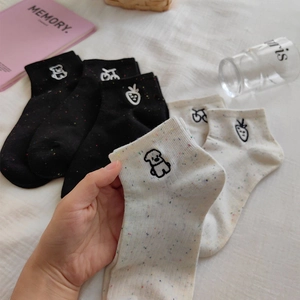 Detailed close-up of cotton socks featuring rainbow confetti yarn and cute animal embroidery