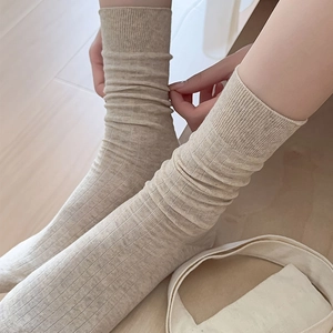 Close-up of beige ribbed cotton mid-calf socks with vertical stripe texture on foot
