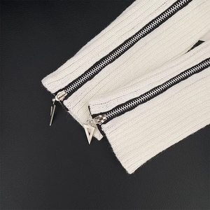 Close-up of white ribbed knit leg warmers with parallel black zippers and silver pullers