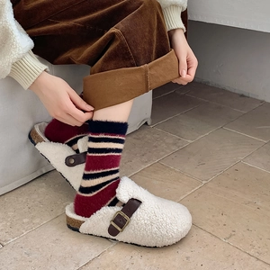Gros plan de sabots en sherpa blanc avec des chaussettes en peluche à rayures rouges