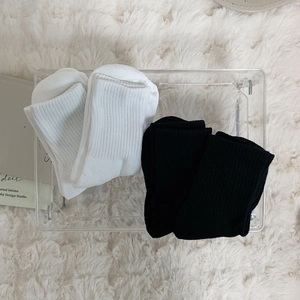 Detailed view of thick black and white rib-knit crew socks on a soft plush carpet