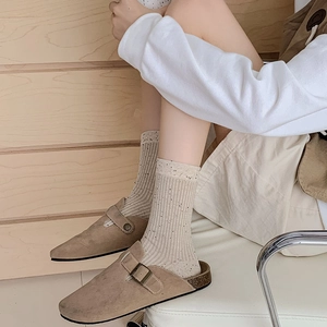 Close-up of beige ribbed knit socks with flecked yarn and khaki suede buckle mules