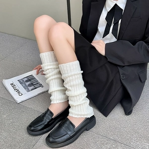 Jambières tricotées blanches à côtes portées avec des mocassins noirs style JK