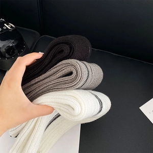 Detailed view of knitted leg warmers in three colors with side zippers and ribbed texture