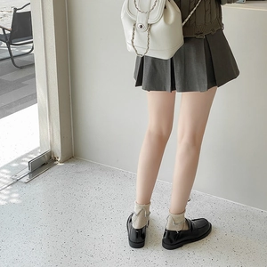 Rear view of a white leather bucket backpack with silver chains and black loafers