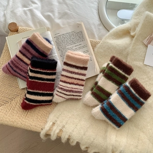 Gros plan de cinq paires de chaussettes en peluche à rayures épaisses aux tons d'automne