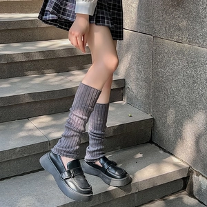Détail de jambières en tricot gris foncé avec des mocassins noirs à semelle plateforme
