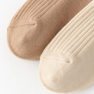 Detail of vertical ribbed knit texture on camel and beige over-the-knee socks for women
