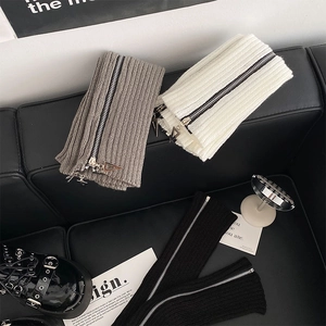 Close-up of ribbed knit leg warmers with metallic side zippers in black, grey, and white