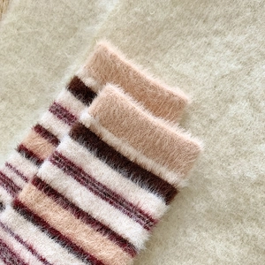 Gros plan de chaussettes en fausse fourrure à rayures douces en beige et marron chaud