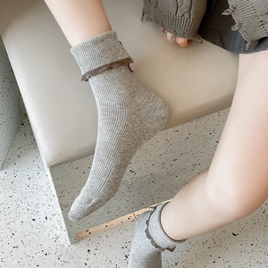 Detail of light gray knit socks with brown ruffle trim and vertical ribbed texture