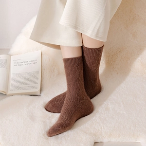 Detail of warm brown knit wool socks with rib texture on a white plush rug